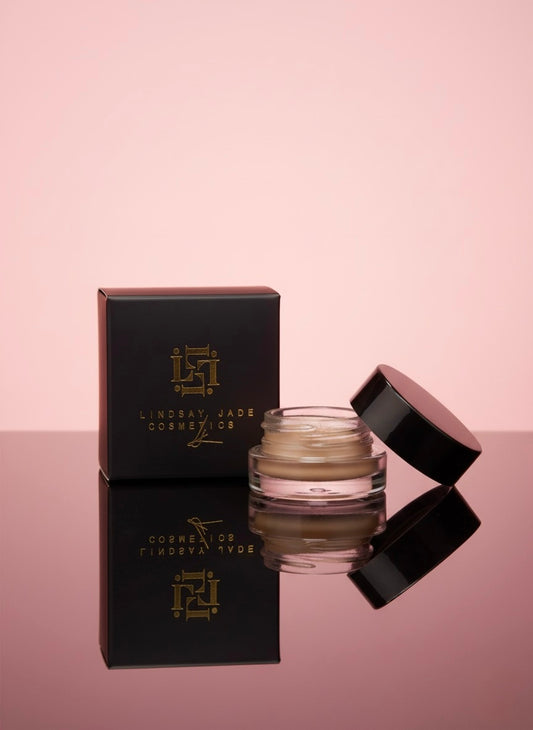 Cosmetic jar with lid open and packaging on a pink background