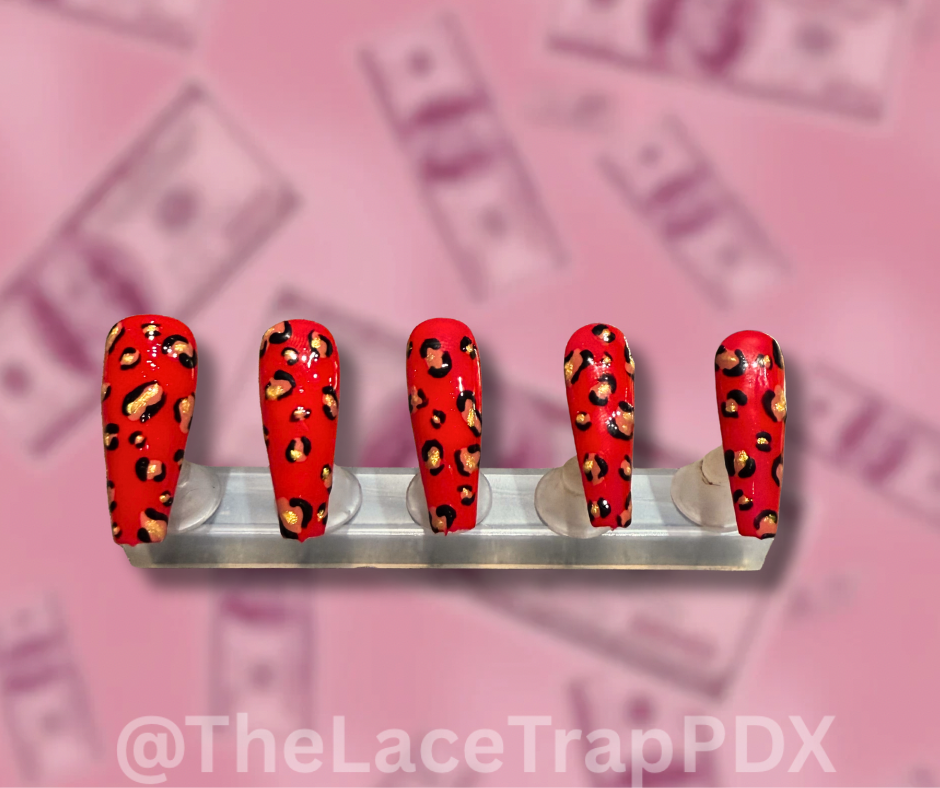 Red press on nails with black and gold leopard print design displayed on a stand long coffin shape perfect for bold stylish looks