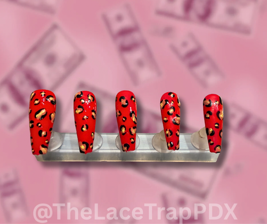 Red press on nails with black and gold leopard print design displayed on a stand long coffin shape perfect for bold stylish looks