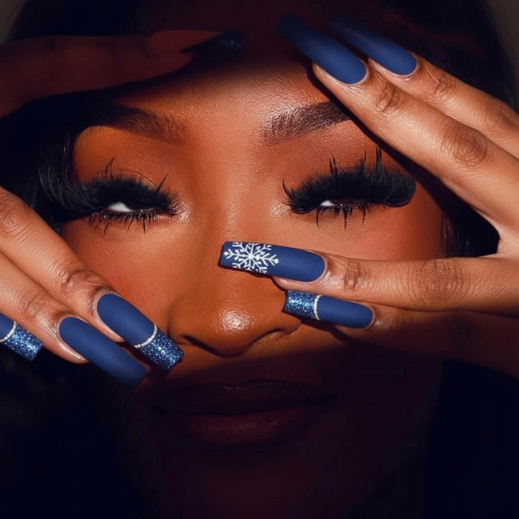 Close-up of a person with blue press on nails and a snowflake design, against a dark background 